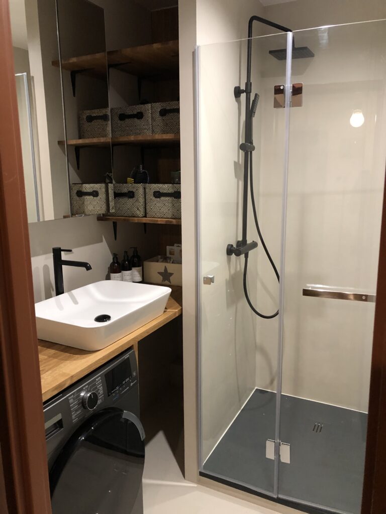 Wałbrzych – kapitalny remont łazienki, mikrocement w kolorze warm beige, paski dekoracyjne we wnęce prysznicowej, lakier satynowy.